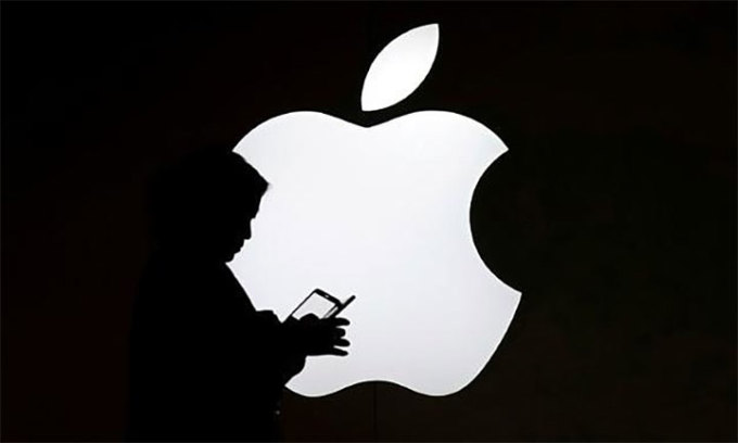 Vào tháng 7 năm 2017, một người phụ nữ đứng trước logo Apple và sử dụng điện thoại thông minh bên ngoài một cửa hàng ở Thượng Hải.Ảnh: Reuters